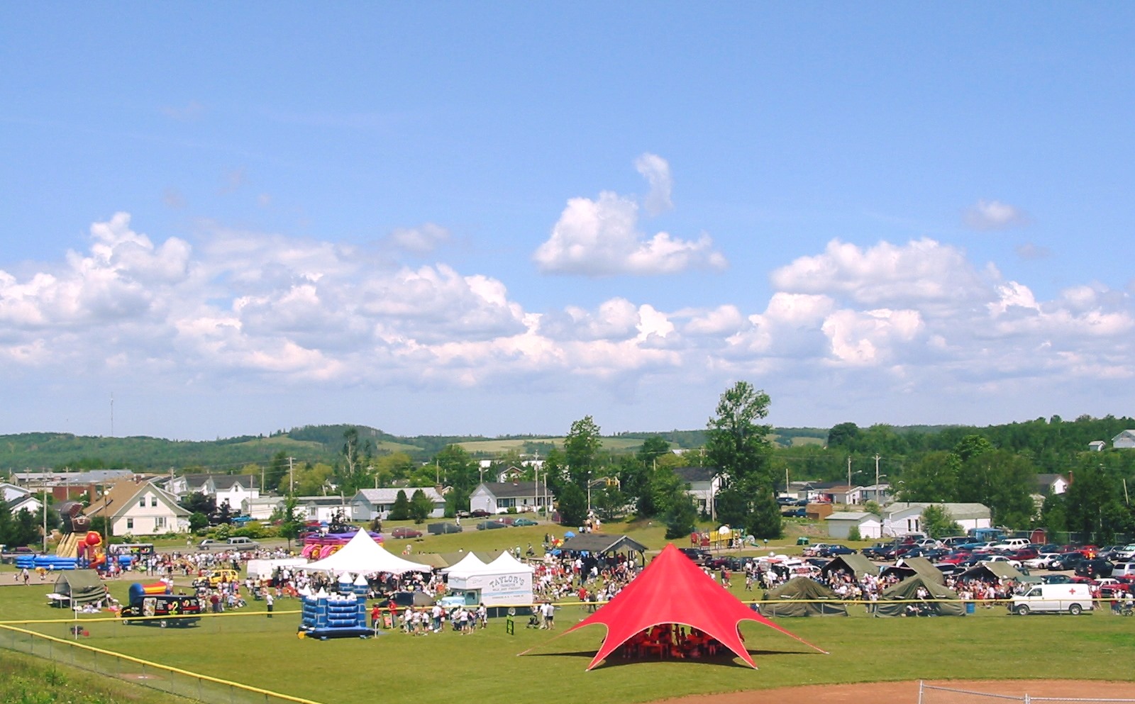 Far away picture of Bible Hill Recreation Park during Canada Day celebrations, with the sky, tents and bouncy castles in view